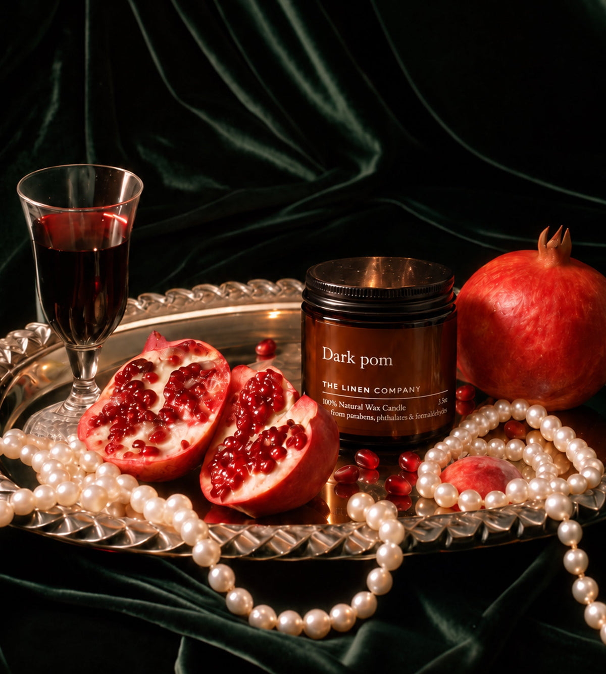 Dark Pom scented candle on green velvet with pomegranates and pearls
